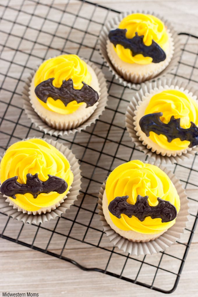 Batman cupcakes sitting on a cooling rack, picture taken from the top. 