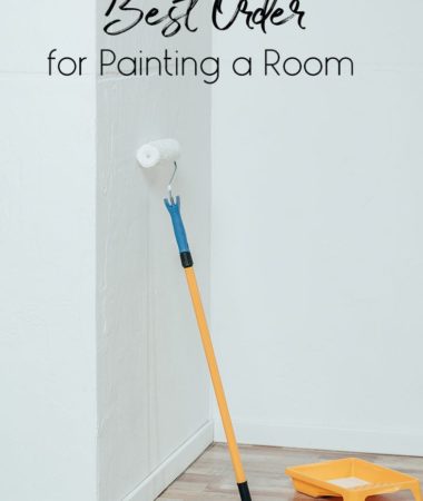 A paint roller leaning against a white wall, waiting to be used for painting.