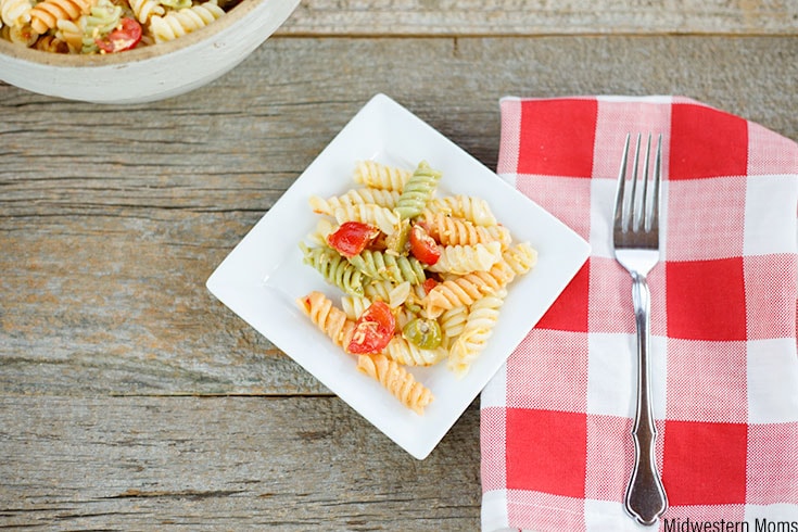 Zesty Italian pasta salad on a small white square plate with red and white checkered napkin to the right.