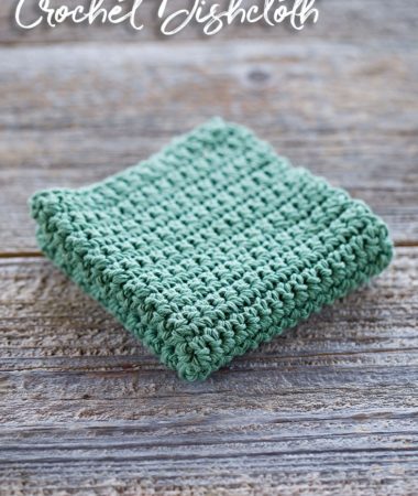 Sage Green crochet dishcloth that is folded in quarters is sitting on old barn wood background. The dishcloth is made with single crochet stitches.