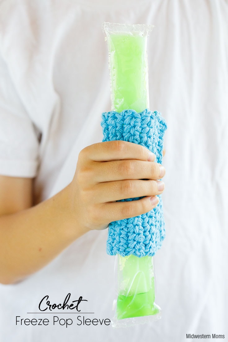 Child holding a freeze pop with a crochet sleeve to protect their hands from the cold.