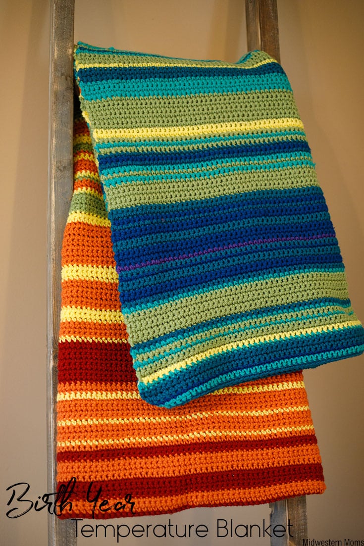 A crocheted temperature blanket draped over a blanket ladder.