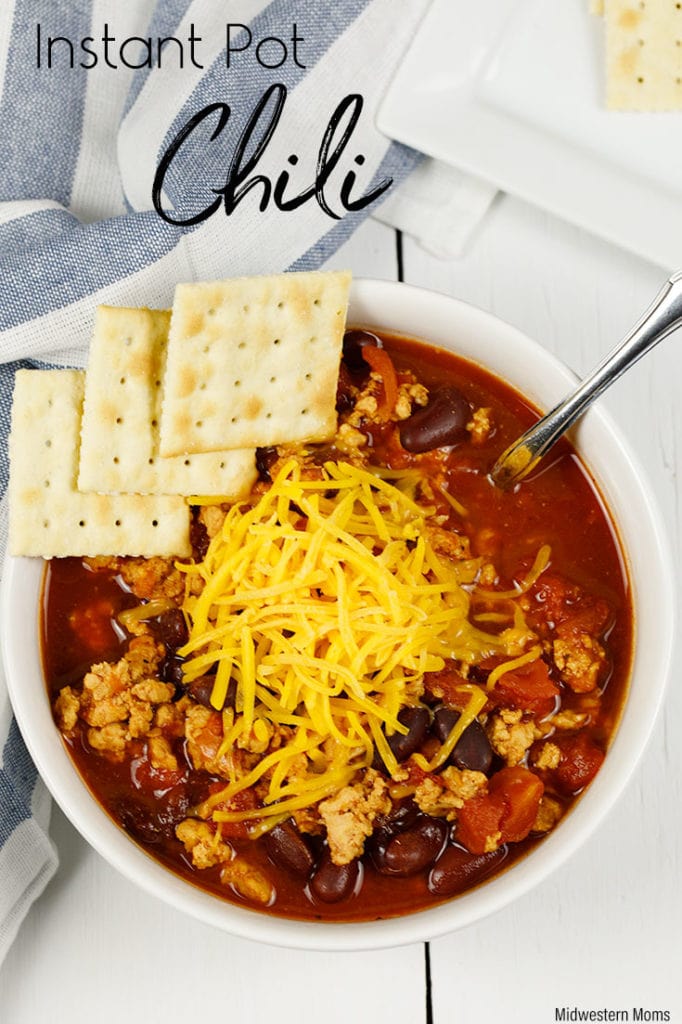 Delicious chili in a white bowl. Chili is topped with cheese and crackers and it was made in an Instant Pot.