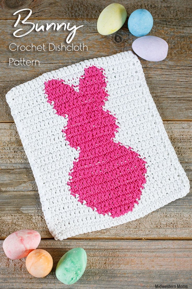 A white crochet dishcloth with a bright pink bunny on it.