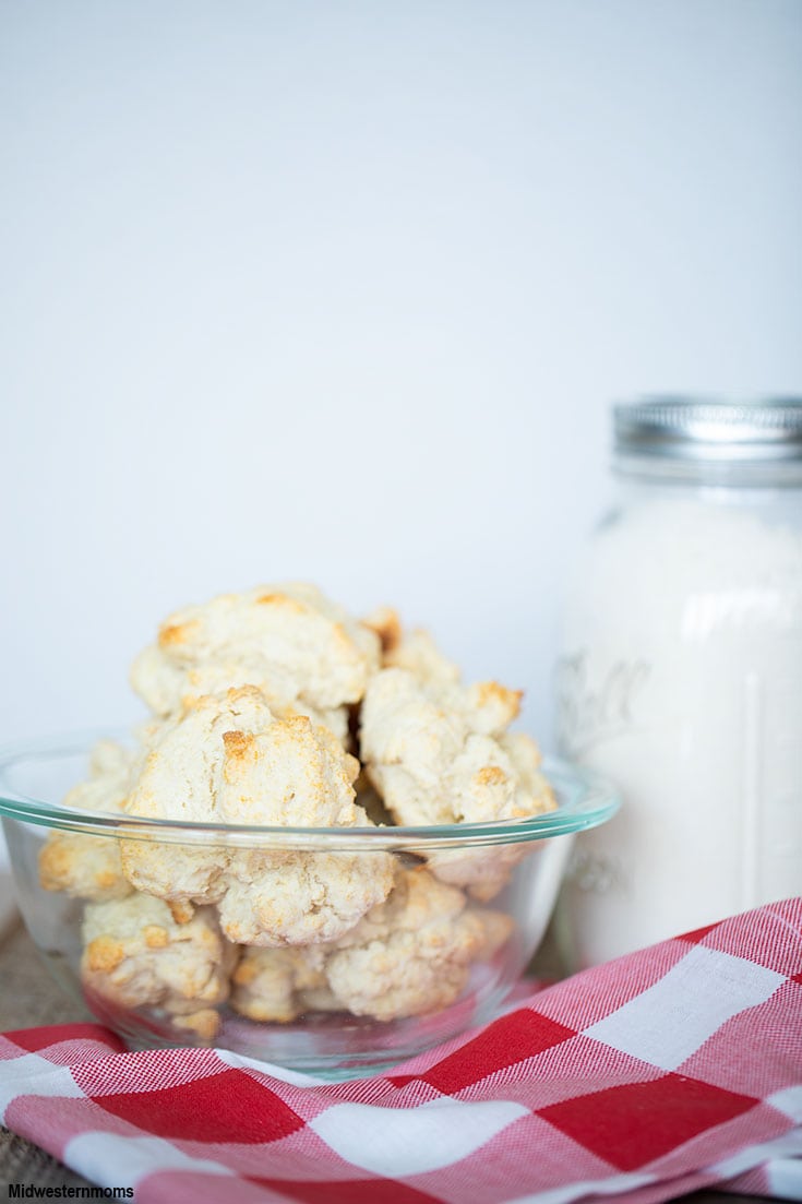 A bowl of homemade bisquick biscuits sitting next to a jar of mix.