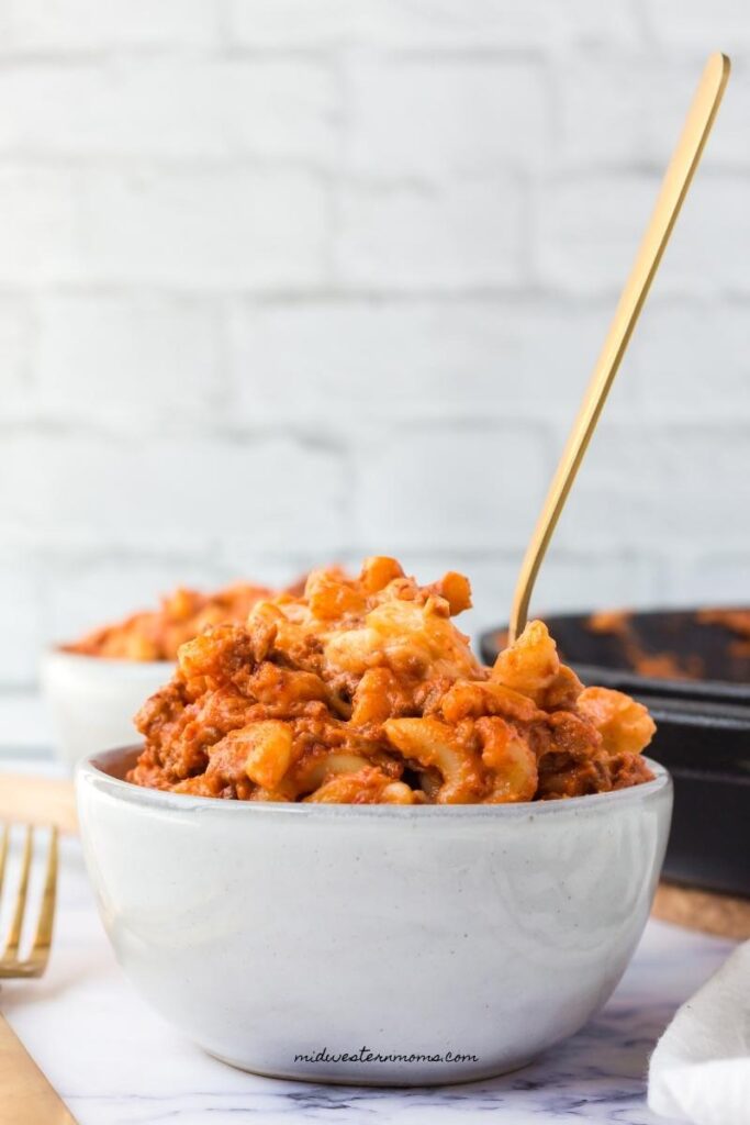 a white bowl with sloppy joe mac and cheese sitting on a table